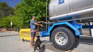 Un vecino ofrece agua de la cuba a su perro. 