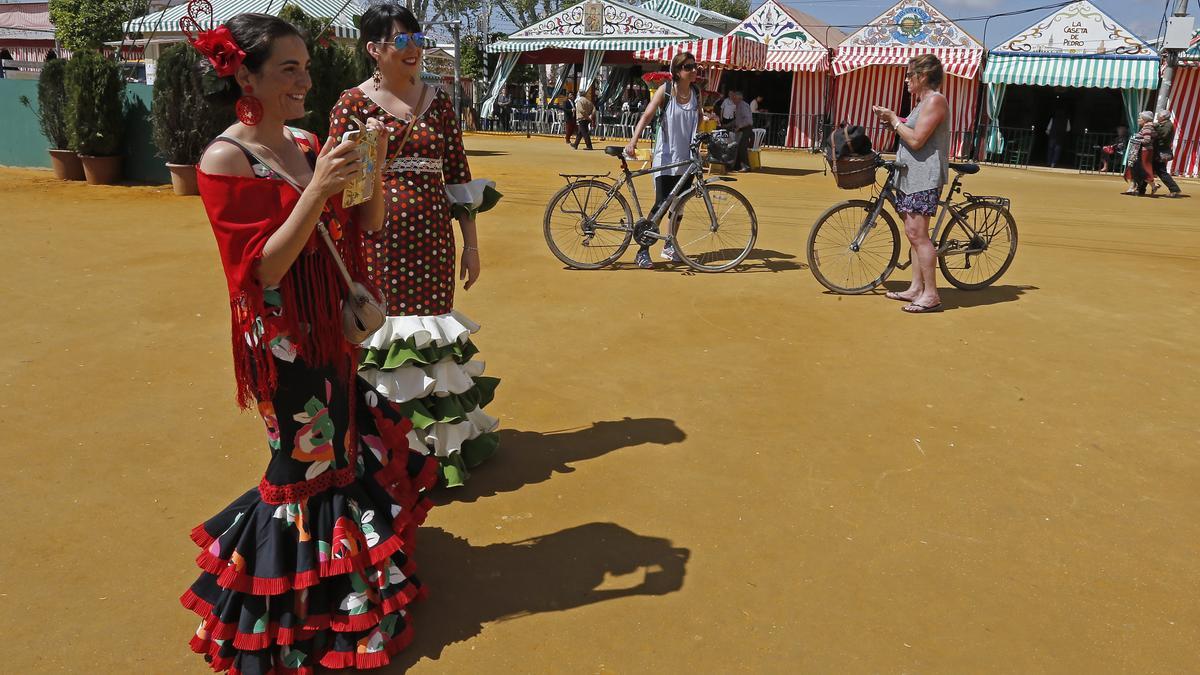 Dos turistas pasean en bici por el Real de la Feria de Sevilla