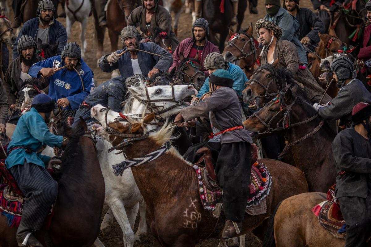 Jinetes afganos compiten en un deporte tradicional de Asia Central, en el que los jugadores montados a caballo intentan colocar una bolsa que se asemeja a un cadáver de cabra en una portería