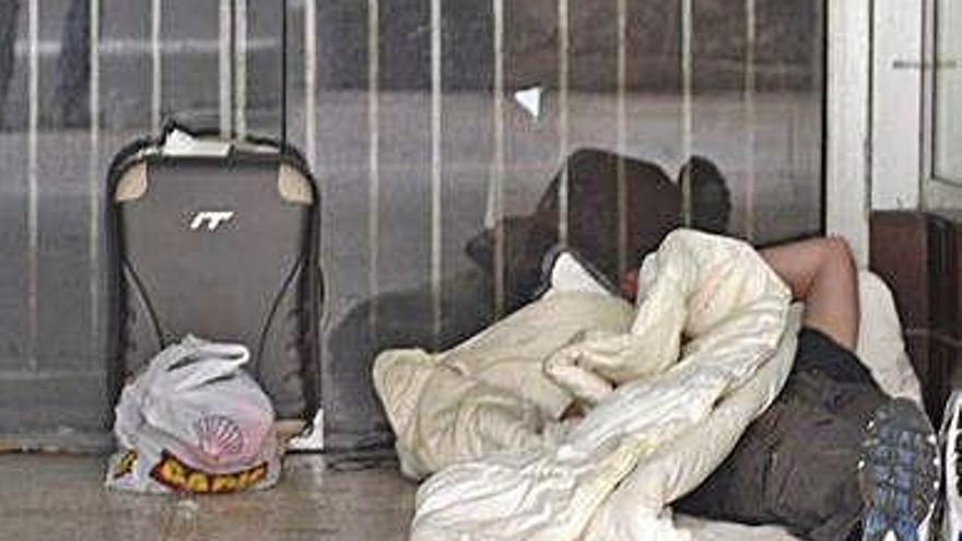 Una persona duerme en la entrada de una tienda vacía.