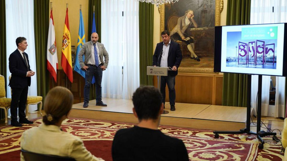 David Rionda presenta el Foro de Ciudades por el Empleo ante la mirada del edil Santos Tejón y, a la izquierda, Jaime López, de la organización, en el salón de recepciones del Ayuntamiento. | Irene Sirgo