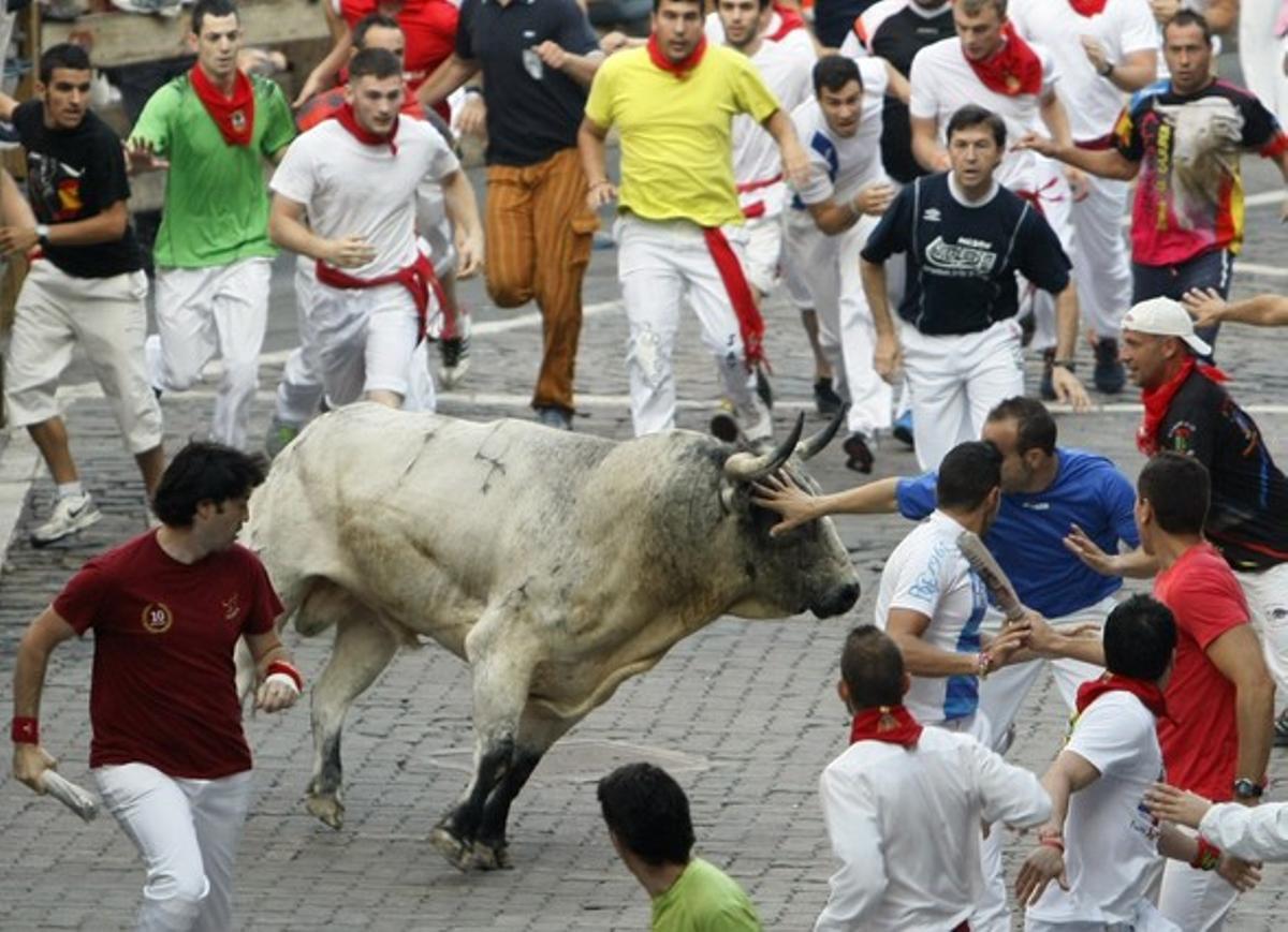 Un corredor posa la mà en l’ull d’un toro a l’entrada de la plaça.