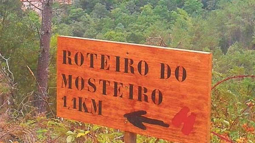 Uno de los carteles indicadores, con el cenobio al fondo.