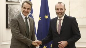 El primer ministro griego, Kyriakos Mitsotakis, estrecha la mano del líder del Partido Popular Europeo, Manfred Weber, este jueves en Atenas.