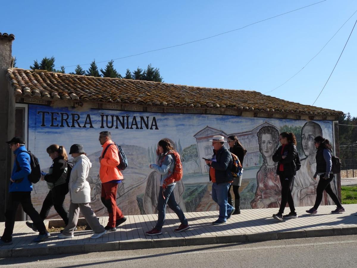 El professorat passa per davant el mural on Toni Espinar posa rostres a la família Iuniana.