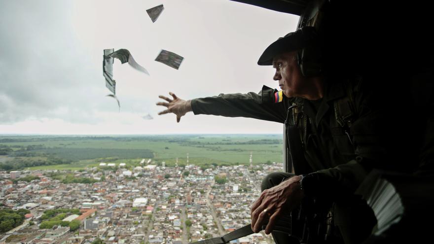 Un oficial de la Policía lanzando volantes informativos desde un helicóptero en la región colombiana de Urabá en una campaña para invitar a la comunidad a denunciar la ubicación de los jefes del Clan del Golfo.