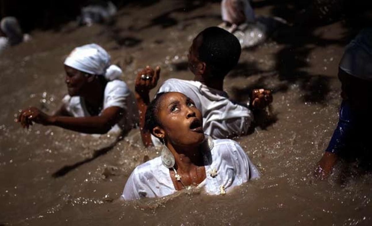Unes dones neden en una piscina sagrada vodú a Souvenance (Haití) aquest diumenge. Centenars de fidels viatgen a aquesta ciutat per Pasqua per mostrar la seva devoció als esperits.