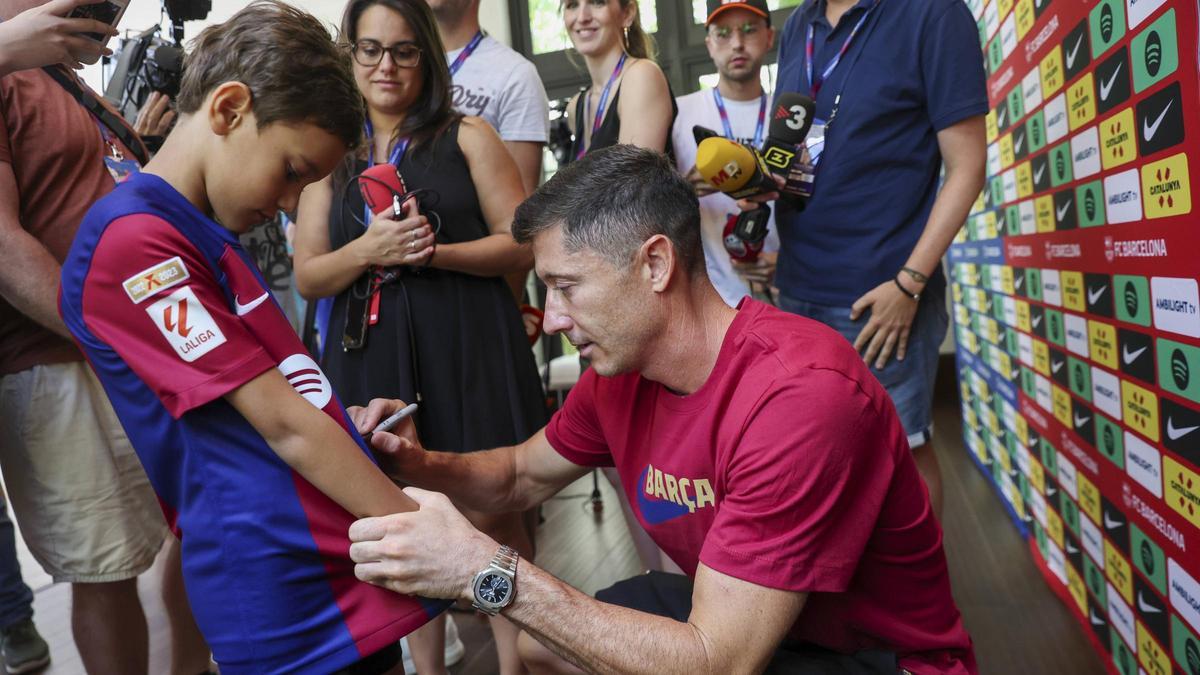 Lewandwoski firma un autógrafo a un niño seguidor del Barça.