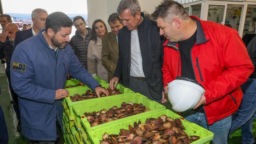 El presidente de la Xunta con el alcalde y el patrón mayor ante unas cajas de volandeira. |  I. Abella