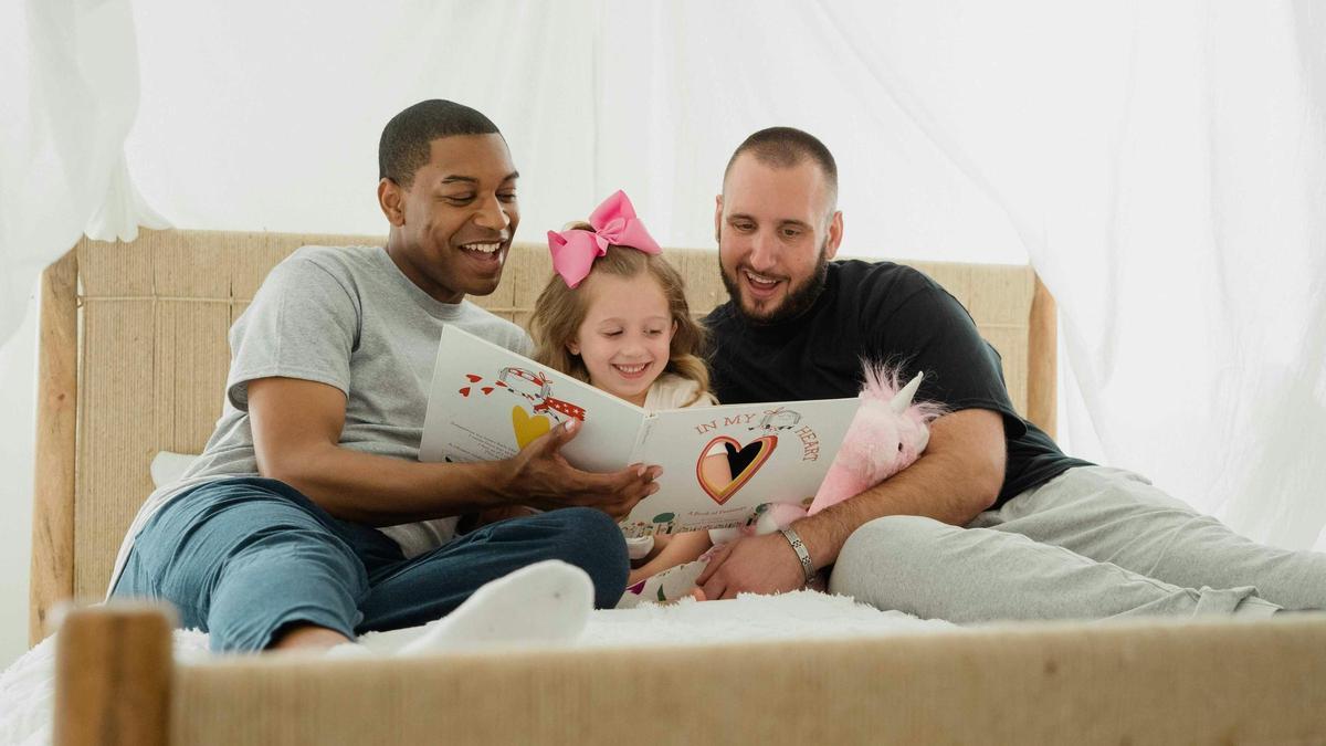 Unos padres leyendo un libro con su hija.