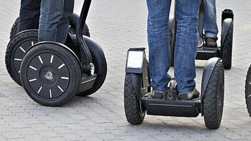 Varios turistas pasean con patinetes eléctricos alquilados en el paseo marítimo de Marbella.