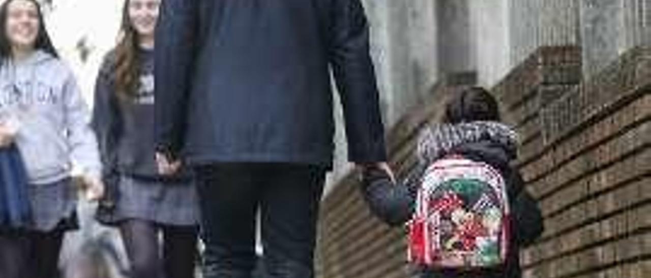 Un padre con su hija de la mano a la salida del colegio.