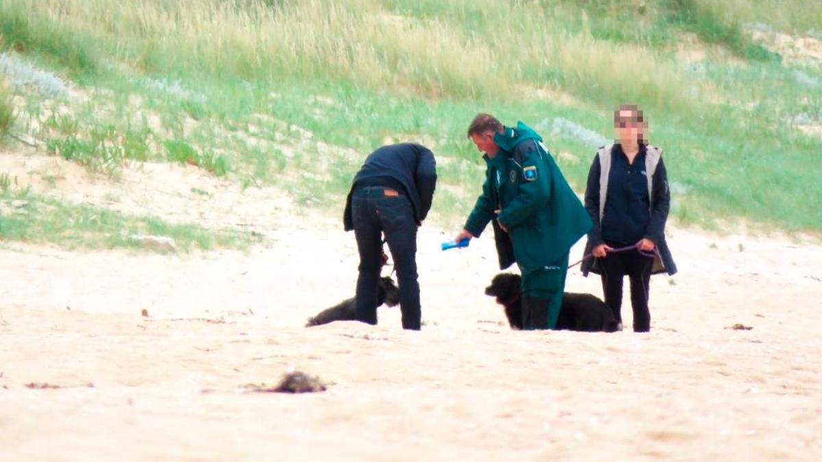 Un vigilante de Medio Ambiente toma los datos a dos usuarios con perros, en A Lanzada.