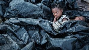 Enia Joaquin Luis se despierta junto a su hermana Luisa bajo los plástico para protegerse de la lluvia mientras se refugian en las gradas del Ring Ring en Buzi Mozambique.