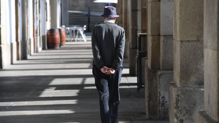 Una persona mayor paseando en solitario por los soportales de la plaza de María Pita. |   // CARLOS PARDELLAS