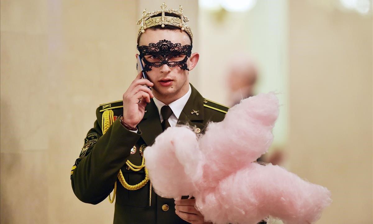 Un cadete militar de Bielorrusia sostiene un algodón de azúcar, mientras habla por su teléfono móvil durante el Baile de Año Nuevo en el Teatro Bolshoi de Ópera y Ballet de Minsk.