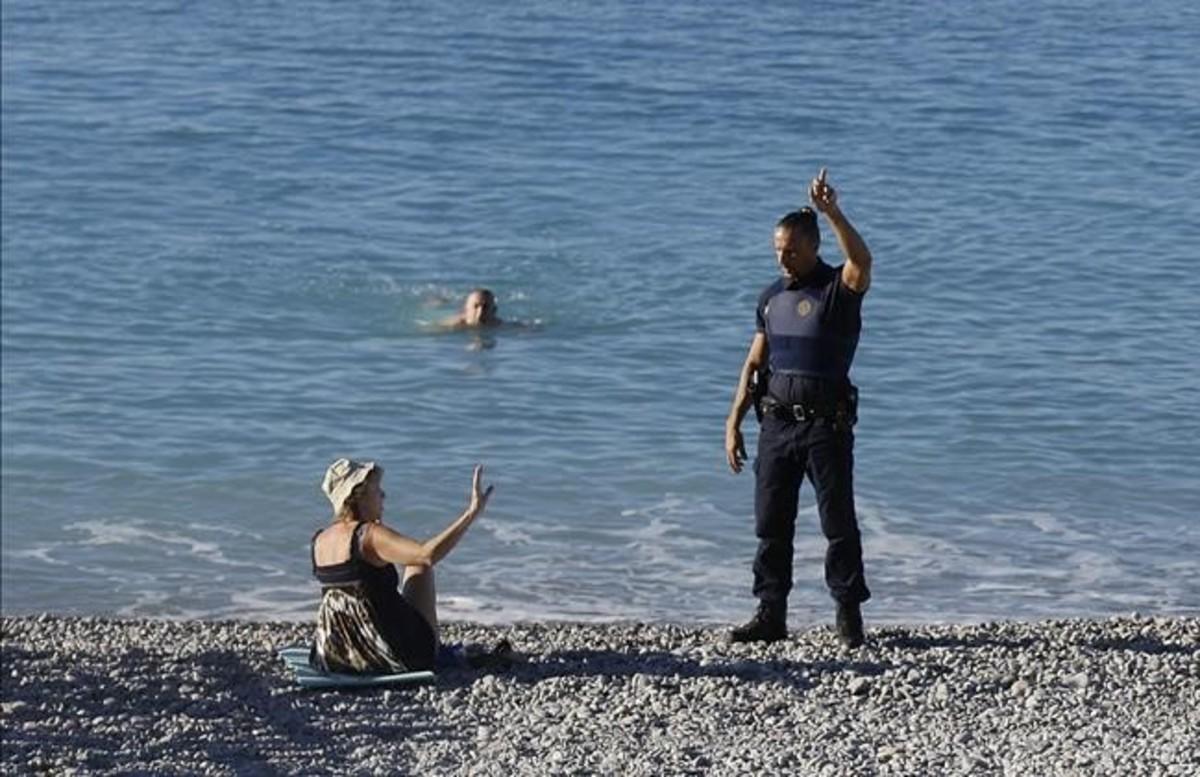 Un gendarme ruega a una bañista abandonar la playa, junto al Paseo de los Ingleses