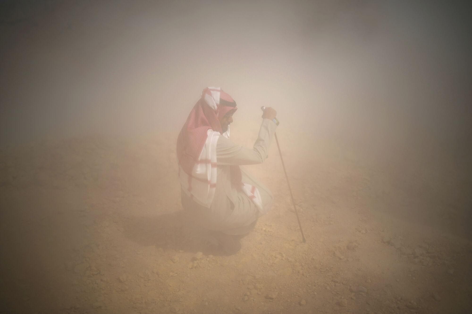 A man protects himself from dust during the ninth stage of the Dakar Rally between Riyadh and Haradh, Saudi Arabia, Tuesday, Jan. 14, 2025. (AP Photo/Christophe Ena)
