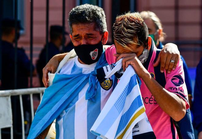 Los aficionados lloran tras salir de la capilla ardiente de Diego Armando Maradona en la Casa Rosada.