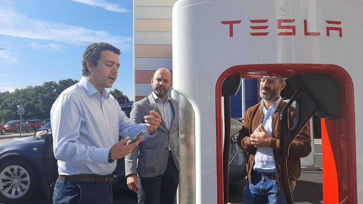 Un responsable de Tesla muestra el funcionamiento de la estación de carga al director de Parque Principado, Fernando García, y al alcalde de Siero, Ángel García, a la derecha. | L. Palacios