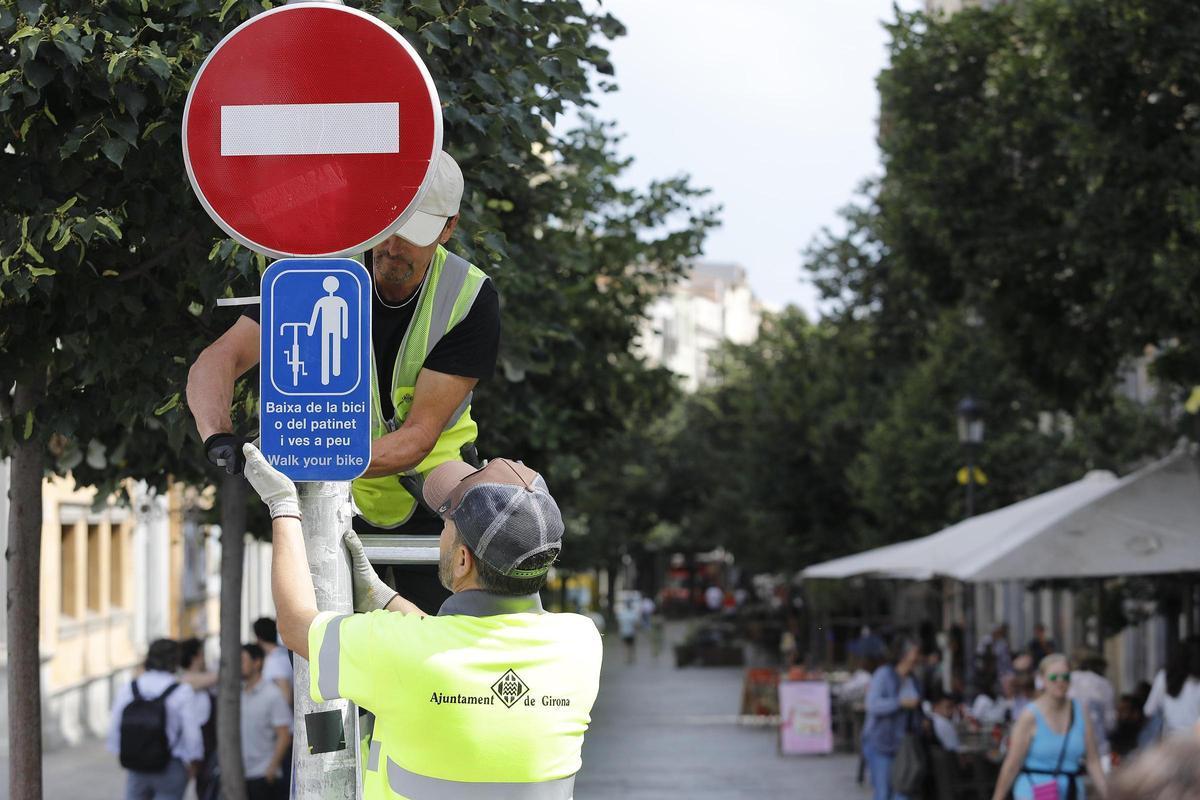 Operaris de la brigada municipal col·locant un senyal.