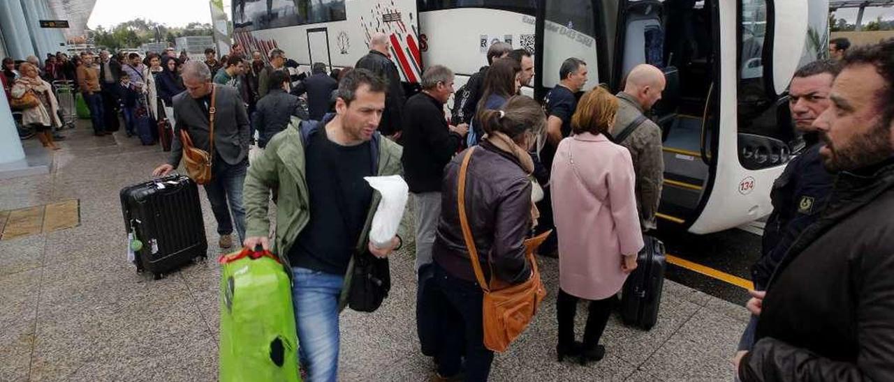 Viajeros suben a un autobús en Peinador tras desviarse su vuelo por la niebla. // Marta G. Brea