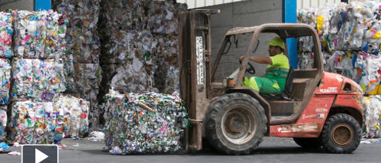 Un trabajador apila basura reciclada.