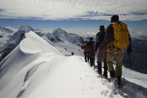 Roped climbers leave the summit of Breithorn on the ridge marking the border between Switzerland and Italy in the Alpine resort of Zermatt