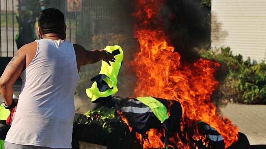 Un empleat d&#039;Acciona llança una armilla a una foguera, a la Zona Franca