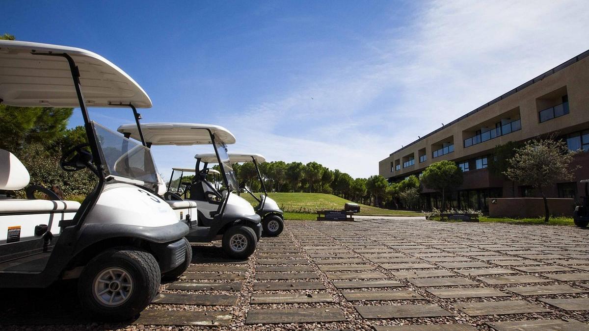 Varios ‘buggy’ de golf aparcados frente al edificio del único hotel del complejo Marina Isla de Valdecañas.