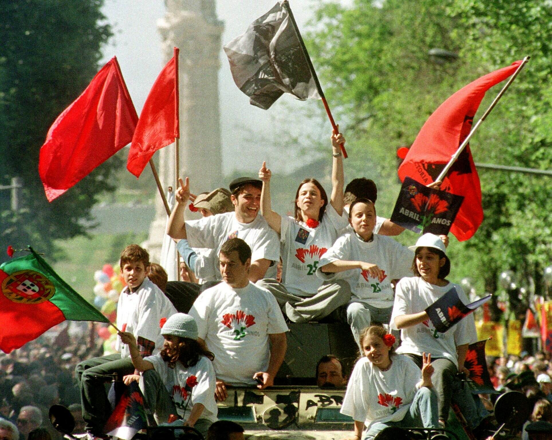 Celebración del 25 aniversario de la Revolución de los Claveles en Lisboa.Youngsters sporting red carnations wave flags, while riding atop a 1970's Portuguese army armored car, during a march down Lisbon's Avenida da Liberdade main avenue, Sunday April 25 1999, commemorating the 25th anniversary of the 1974 Revolution of the Carnations. Thousands gathered in downtown Lisbon to celebrate the army-led bloodless coup toppled a 41-year dictatorship. (AP Photo/Gael Cornier) / Tanque.