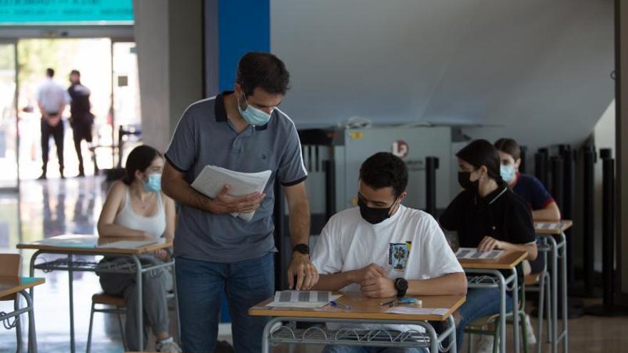 Un profesor reparte un examen a un alumno.