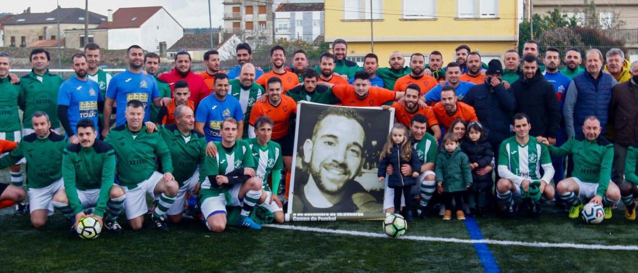 Los jugadores de ambos equipos posan antes del partido junto a la foto gigante de Rubén Acha.  |