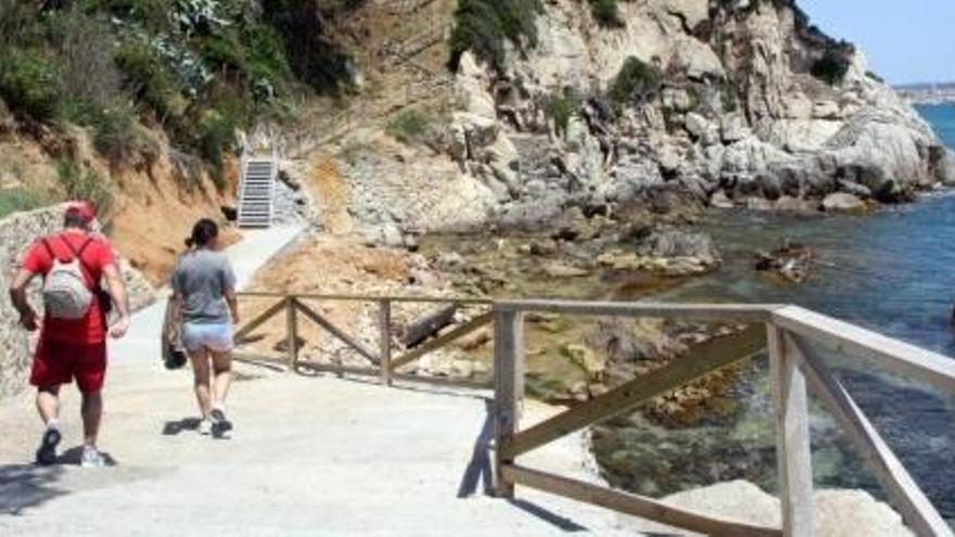 Turistes passejant pel camí de ronda, acabat de reobrir.