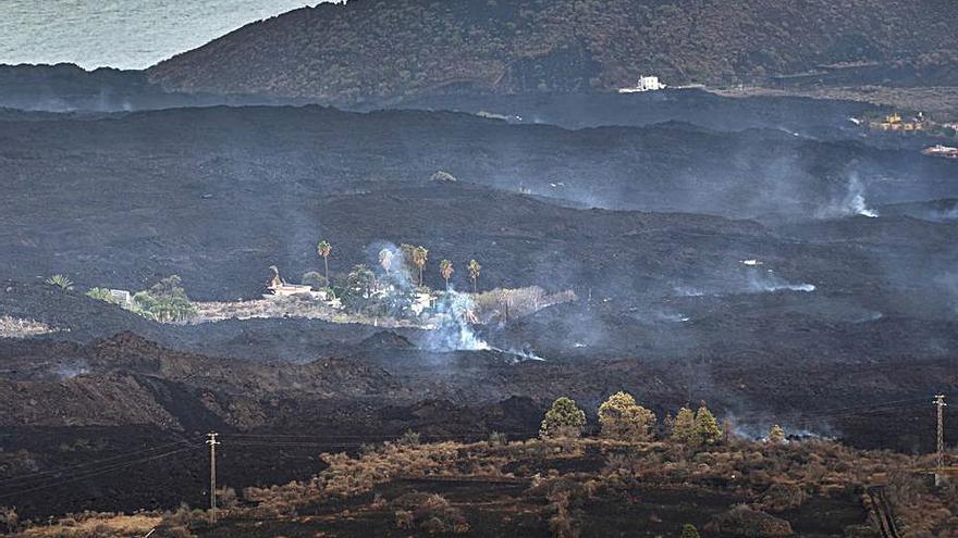 Una de las islas rodeada de lava con la montaña de Todoque de fondo.