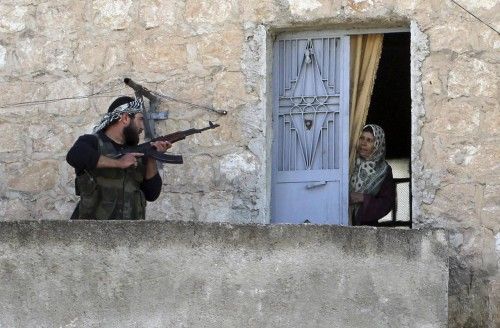 Un miembro del Ejército de Liberación sirio se dirige a una mujer durante una patrulla para buscar las fuerzas progubernamentales en Harem