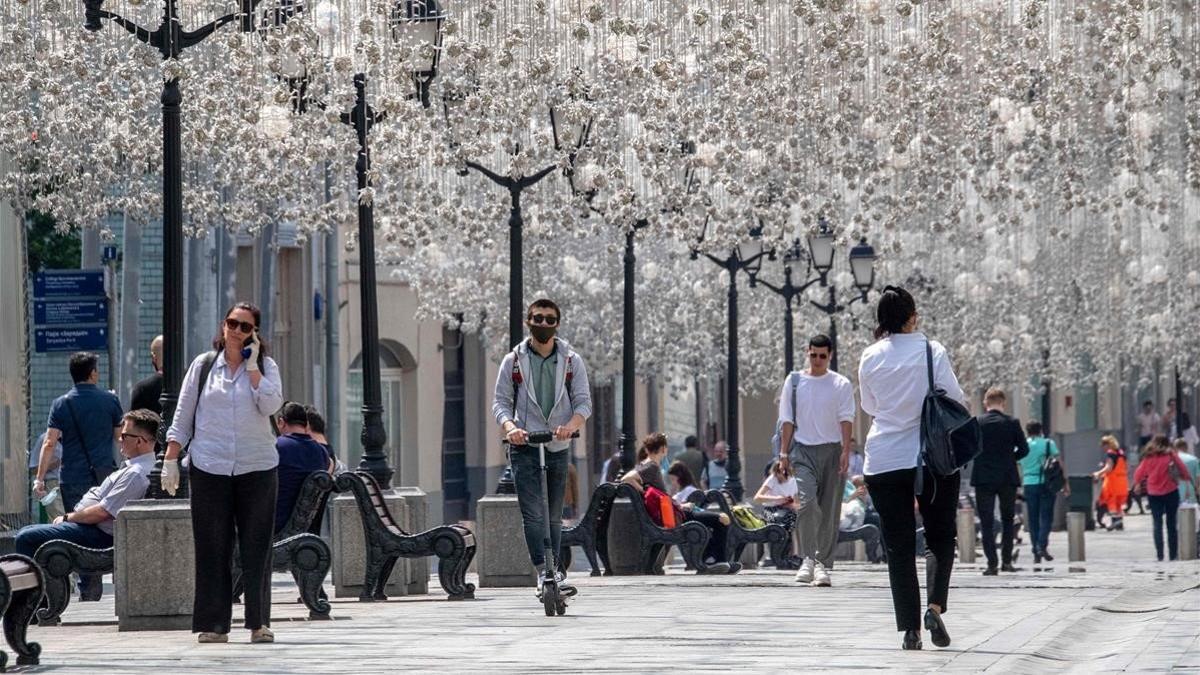 Moscovitas pasean o descansan en bancos en el centro de la capital rusa, este lunes.