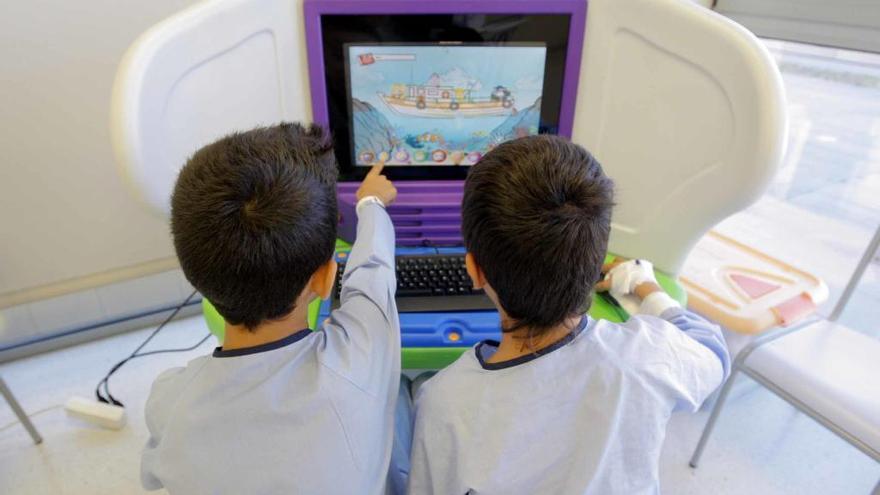 Dos niños hospitalizados se distraen con un videojuego.