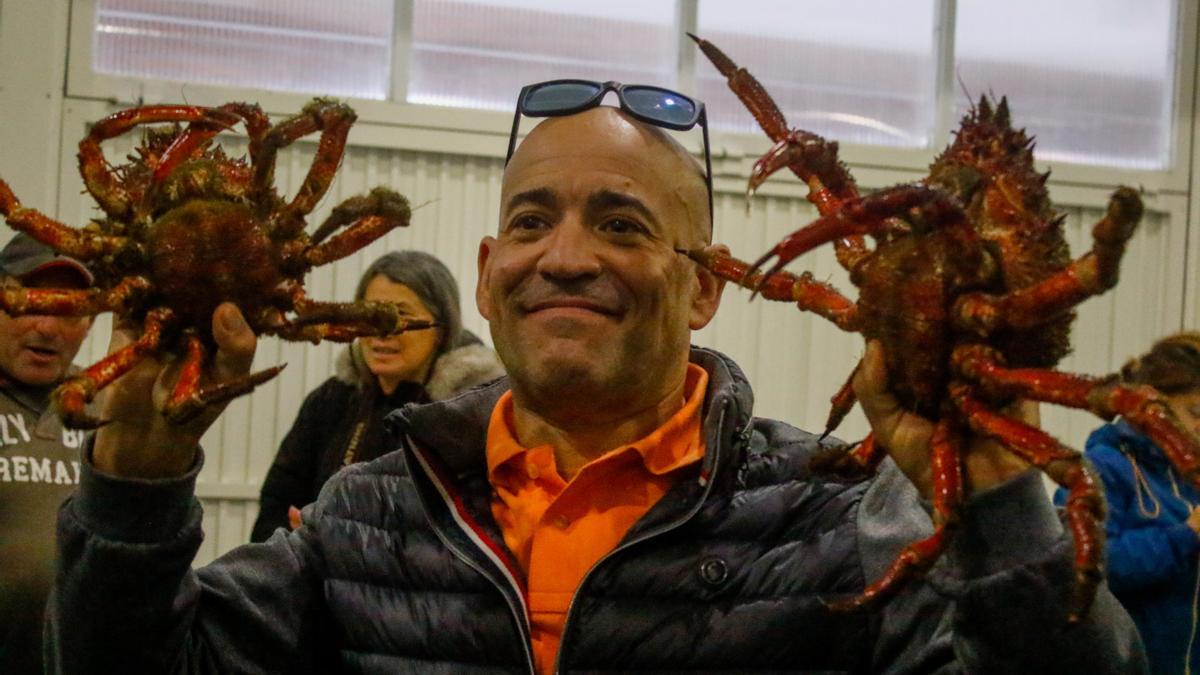 Un hombre muestra dos centollos hembra (centollas) en la lonja grovense.