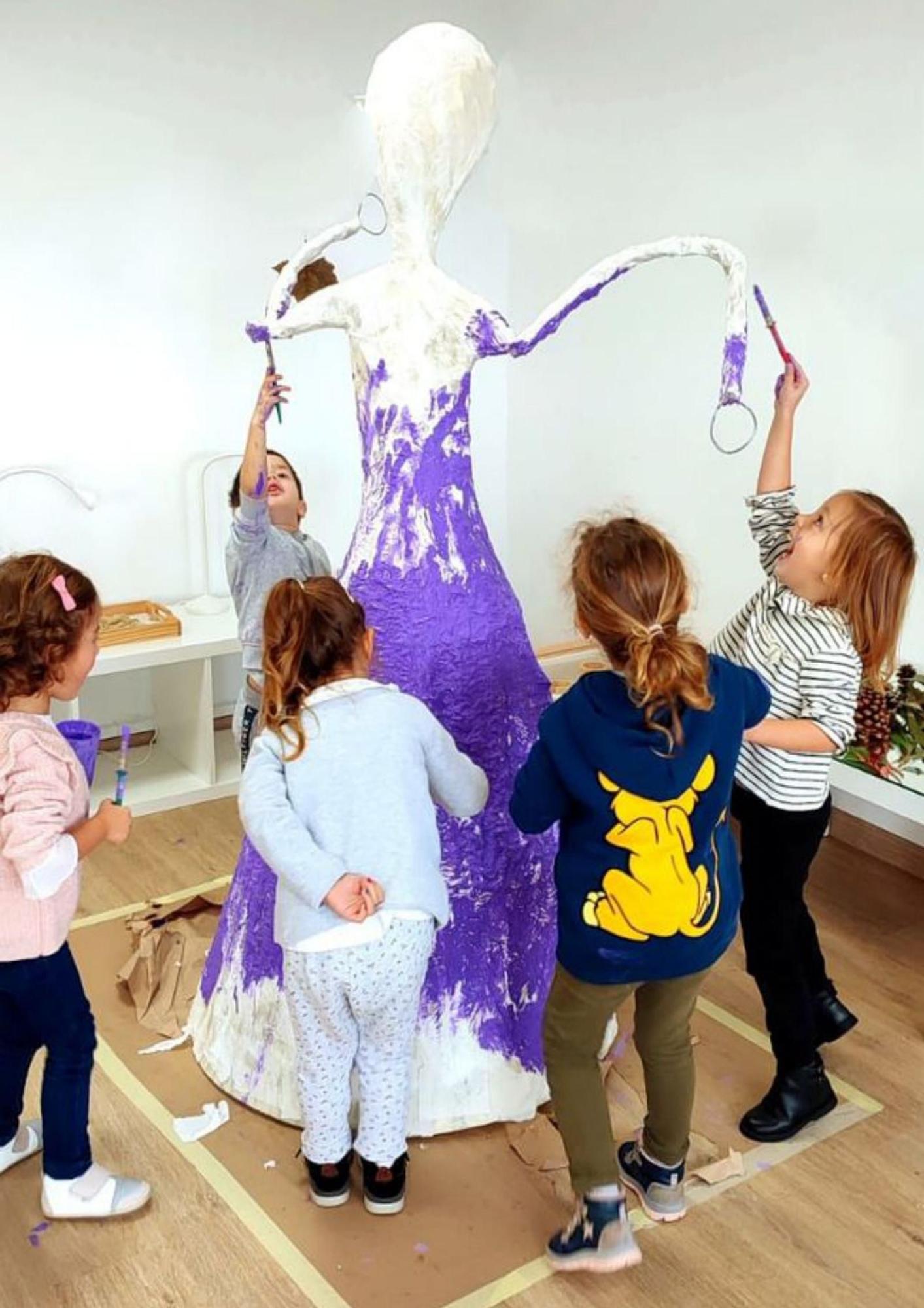 Los alumnos de la escuela unitaria de Donramiro, pintando la escultura.