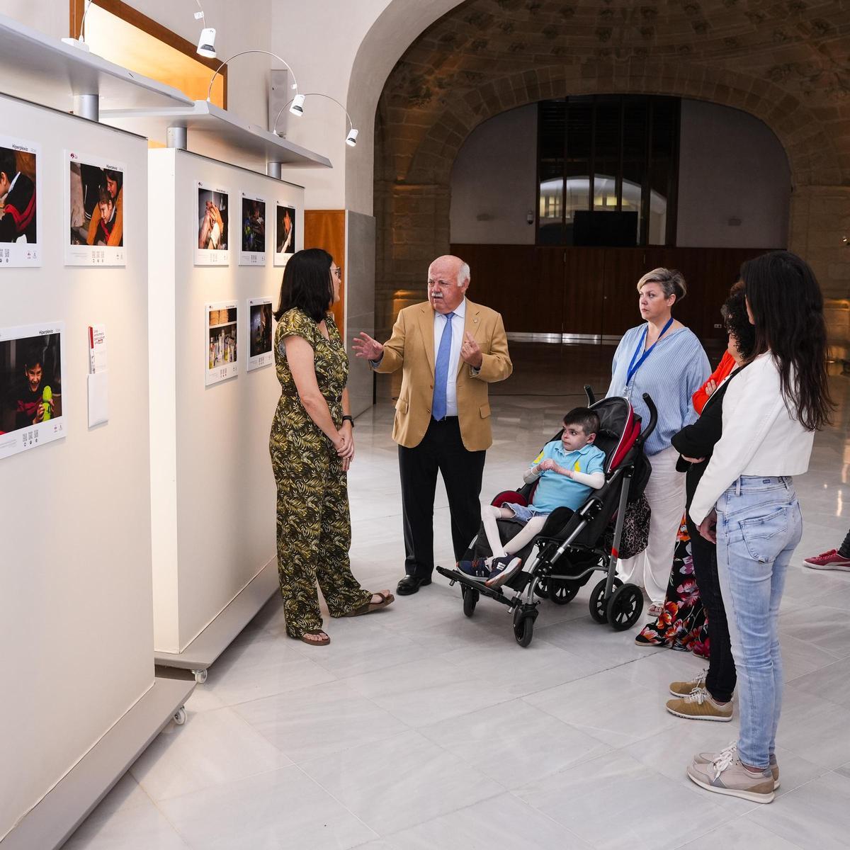 Leo y su madre, Lidia, junto a representantes de Codapa y del Parlamento de Andalucía en la inauguración de la exposición