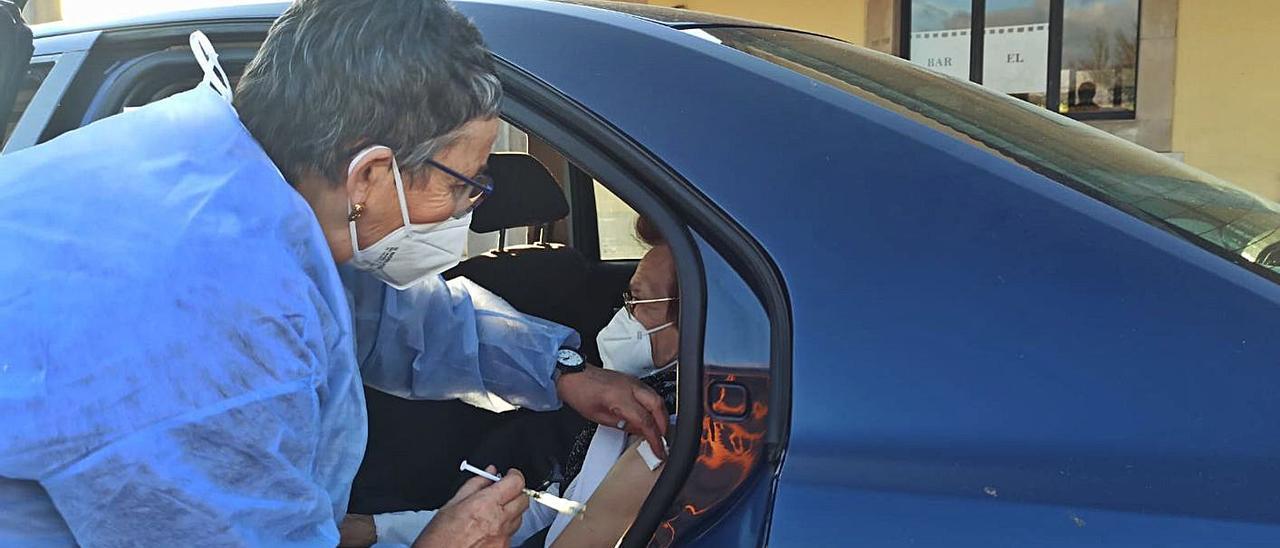 La sanitaria Leni Pellitero inocula la vacuna a Carmen García Saavedra tras ponérsela a su consuegra, Rosa Fidalgo Fernández, en el otro asiento de la parte de atrás del vehículo. Acudieron todos con mucha ilusión y unos pocos nervios | S. ARIAS
