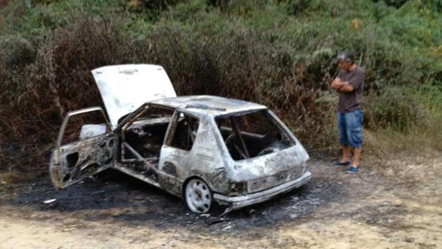 Un vecino contempla el coche totalmente calcinado en Torre (Ribadesella).