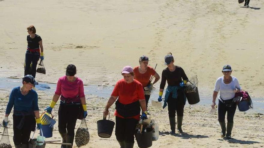 Mariscadoras, ayer, dejando la playa de A Xunqueira con sus capturas. // G.N.