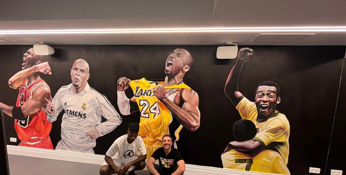 Vinicius y René Mäkelä posan ante el mural 'Idol Wal' que ha realizado el mallorquín para el gimnasio del futbolista