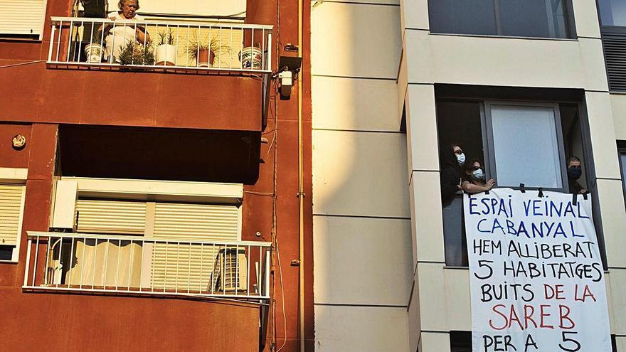 Una vecina se asoma a su balcón mientras miembros de Espai despliegan la pancarta en la finca.