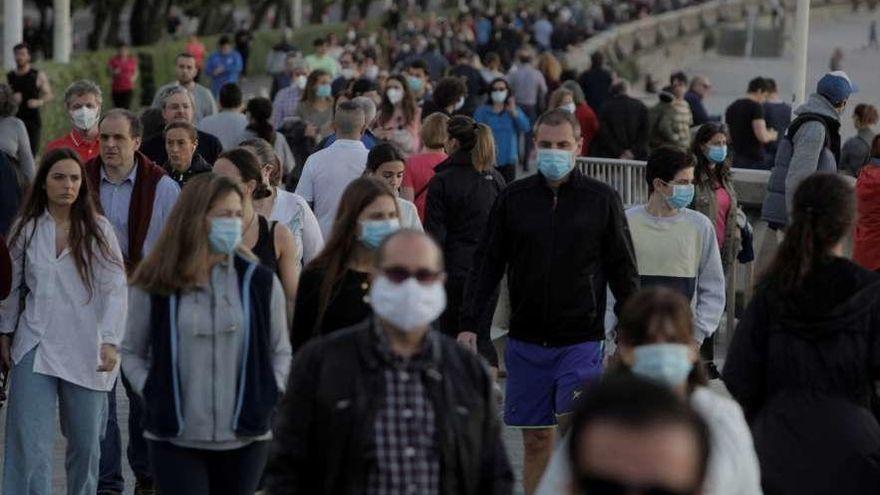 Viandantes en el paseo marítimo de A Coruña con mascarillas.