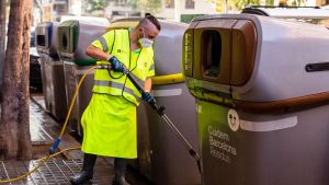Un operari de Cuidem Barcelona neteja amb aigua freàtica els contenidors