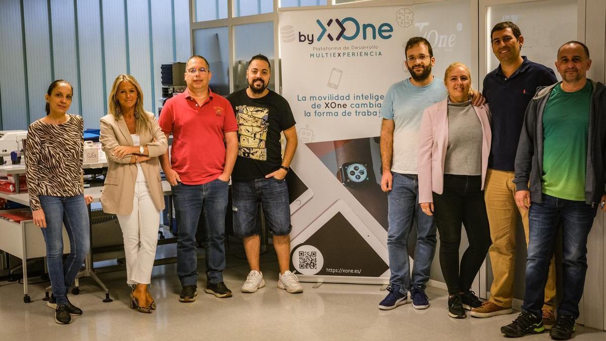 Varios miembros de XOne posan junto a uno de los carteles de la empresa, en Badajoz.
