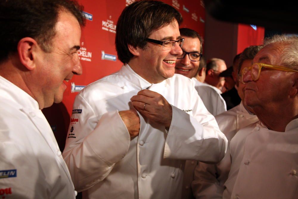 El president de la Generalitat, Carles Puigdemont, es corda la jaqueta de cuiner sota la mirada de Martín Berasategui i Juan Mari Arzak